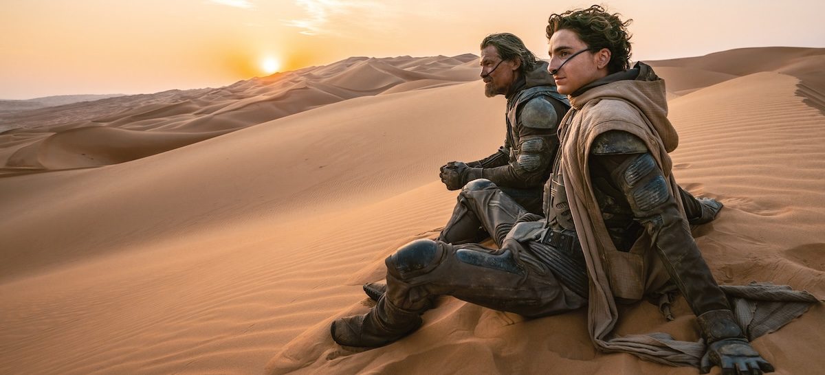 Timothee Chalamet and Josh Brolin in costume smiling as they look out from a sand dune from Dune Part Two: The Photography